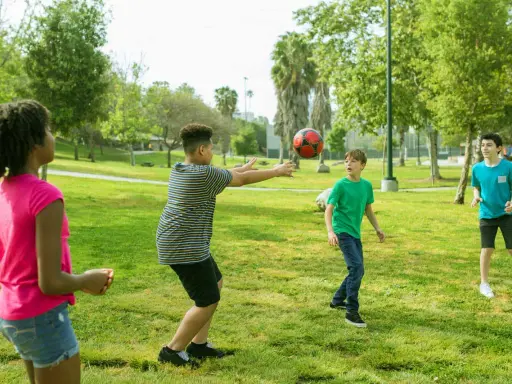 Bambini giocano a pallone in un parco, perfetti giochi per l'estate.