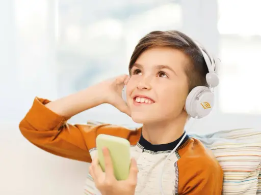 Ragazzo con cuffie bianche ascolta audio fiabe dal suo telefono, immerso in un mondo di storie.