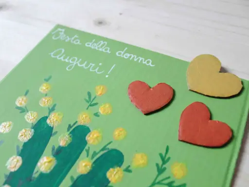 Biglietto fai da te per la Festa della Donna con mimose dipinte e cuori. Idee creative per un augurio speciale.