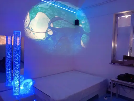 Un'aula snoezelen con proiezioni luminose, colonne d'acqua blu e un letto. Un ambiente rilassante e multisensoriale.