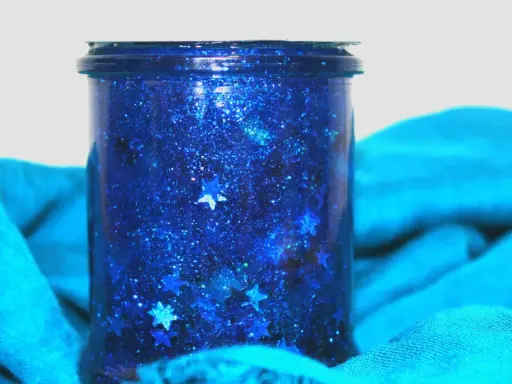 Barattolo della calma fai da te con glitter blu e stelline, un piccolo universo scintillante per rilassarsi.