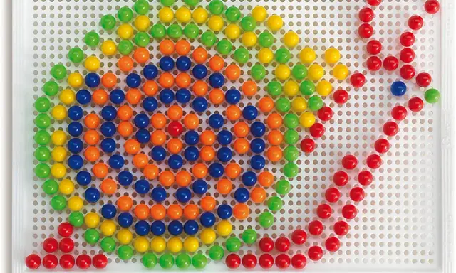 Schemi chiodini gioco: un mosaico colorato di palline verdi, gialle, arancioni e blu su una base bianca, che forma un disegno astratto.