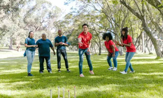 Un gruppo di amici si diverte con i giochi di una volta all'aperto, lanciando anelli in un parco soleggiato.