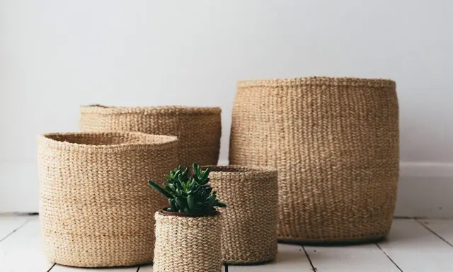 Ceste di vimini di varie dimensioni, una con una piantina. Idee per come abbellire una cesta di vimini con stile naturale.