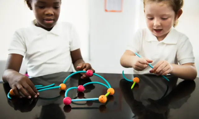 Bambini impegnati in attività sensoriali, costruendo con forme colorate.
