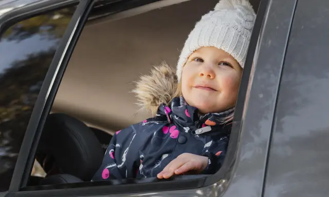 Bambina con cappellino bianco guarda fuori dal finestrino, pronta per i giochi da fare in macchina bambini.