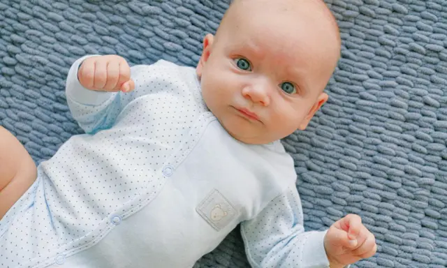 Un neonato con occhi azzurri e un pigiamino a pois, un riflesso di moro autismo nella sua innocenza.
