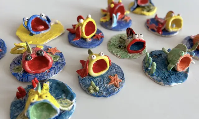 Piccoli pesci colorati, realizzati con la creta, con bocche spalancate e occhi sporgenti, sembrano nuotare in un mare di ceramica.