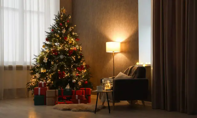 Un albero di Natale addobbato con luci e palline, circondato da regali. Un'atmosfera calda e accogliente, perfetta per capire come si fa l'albero di natale.