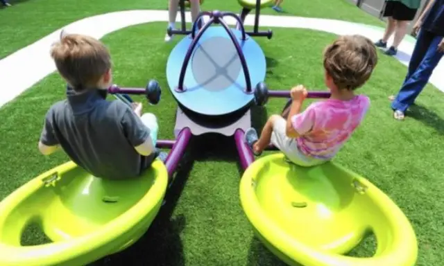 Bambini giocano su giostra inclusiva, pensata per giochi per bambini autistici non verbali.