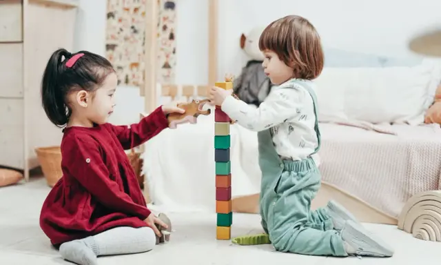 Bambini di 4 anni giocano con blocchi colorati e animali di legno, un'attività divertente e creativa.