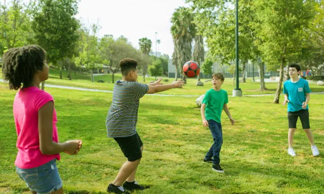 Bambini giocano a pallone in un parco, perfetti giochi per l'estate.