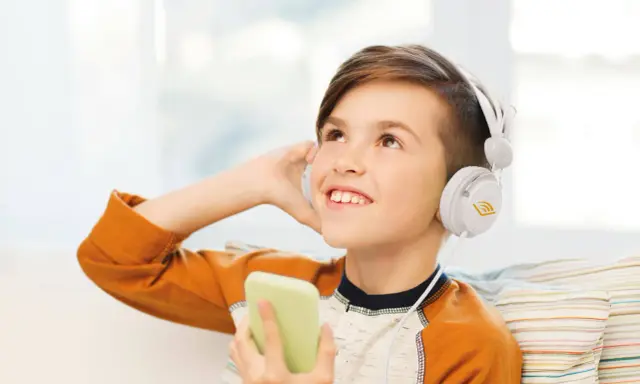 Ragazzo con cuffie bianche ascolta audio fiabe dal suo telefono, immerso in un mondo di storie.