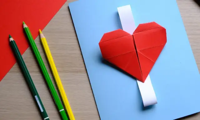 Cuori di carta rossi e matite colorate, pronti per un lavoretto per la festa dei nonni.