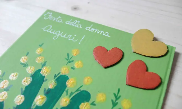 Biglietto fai da te per la Festa della Donna con mimose dipinte e cuori. Idee creative per un augurio speciale.