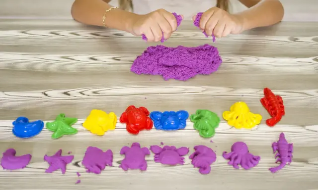 Bambina gioca con sabbia cinetica da che età? Formine marine colorate e viola, un divertimento sensoriale per tutti.