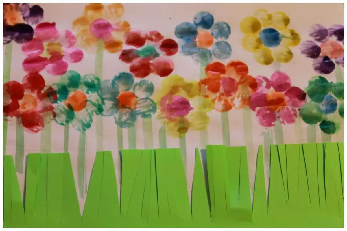 Fiori colorati con impronte di dita, perfetti per frasi sulla primavera per bambini. L'erba verde ritagliata completa il disegno.