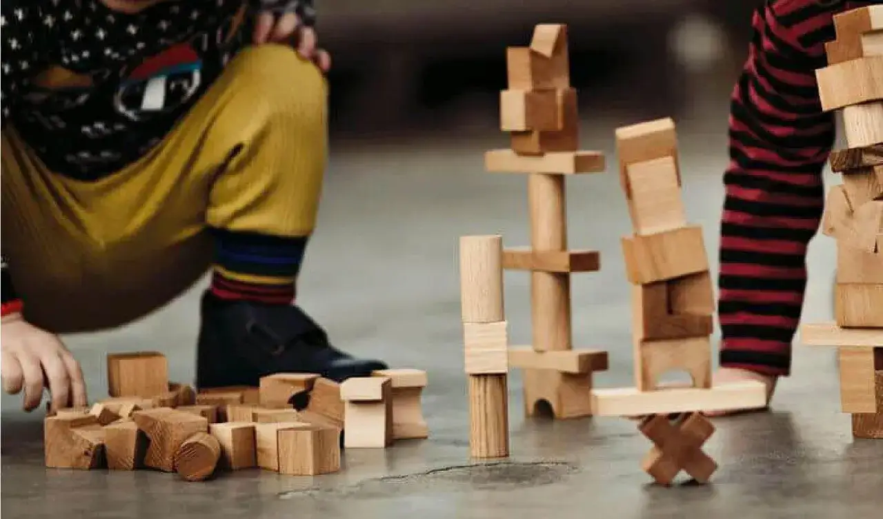 Bambini giocano con blocchi di legno, creando torri e forme. Ecco cosa costruire con le costruzioni: fantasia e creativit&agrave; senza limiti.