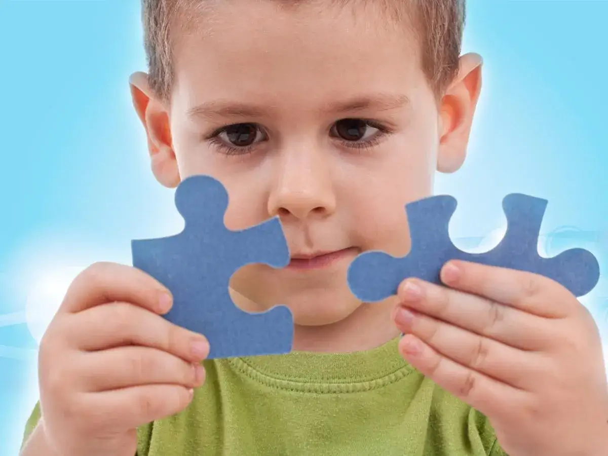 Bambino con disprassia motoria prova a unire due pezzi di un puzzle blu.