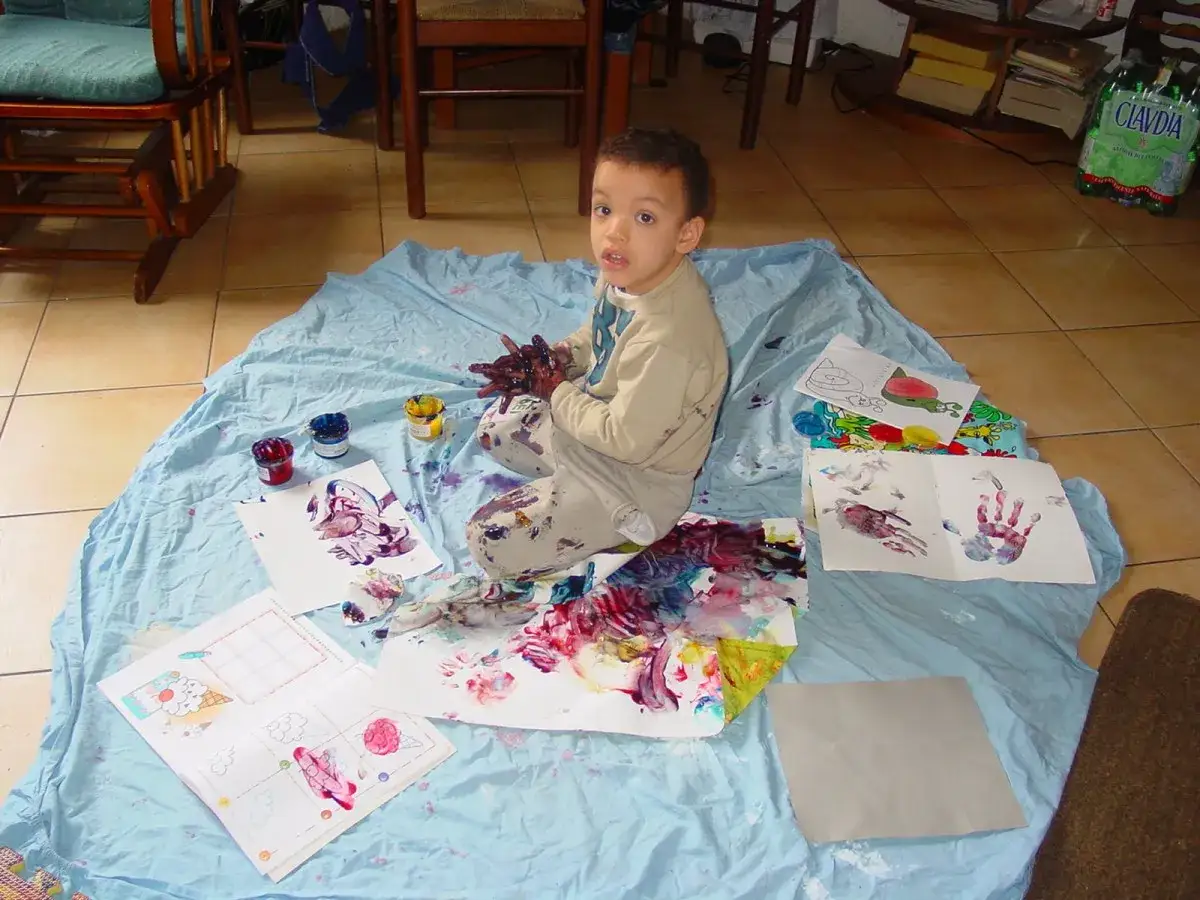 Bambino con mani dipinte esplora colori e texture, un'attivit&agrave; sensoriale per l'autismo.