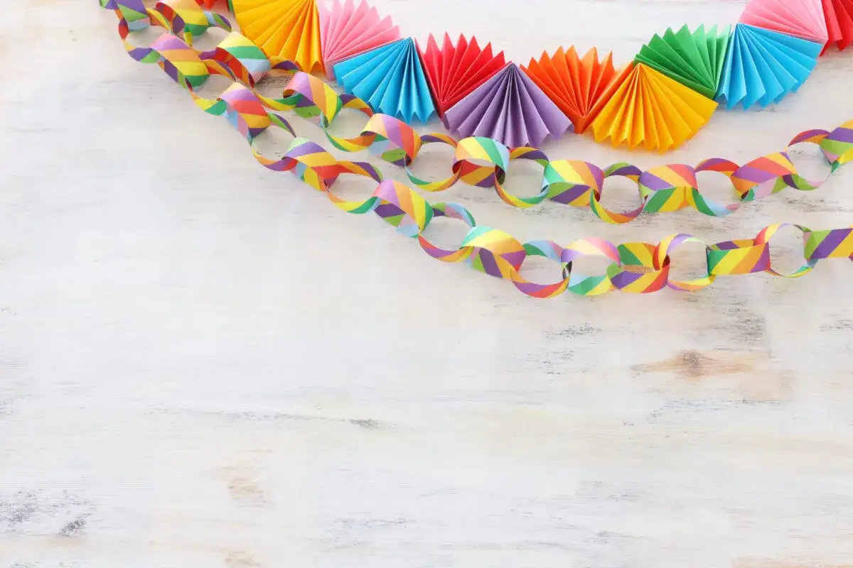 Una colorata catena di carta arcobaleno, con anelli e ventagli di carta, pronta per una festa.