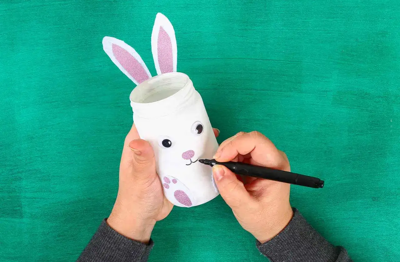 Mani che creano un coniglietto pasquale con un barattolo, uno dei lavoretti di Pasqua bellissimi per decorare la casa.