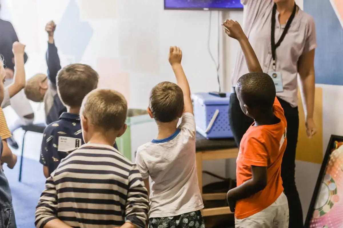 Bambini con le braccia alzate, impegnati in attività che stimolano le funzioni esecutive. Esercizi ludici per allenare mente e corpo.