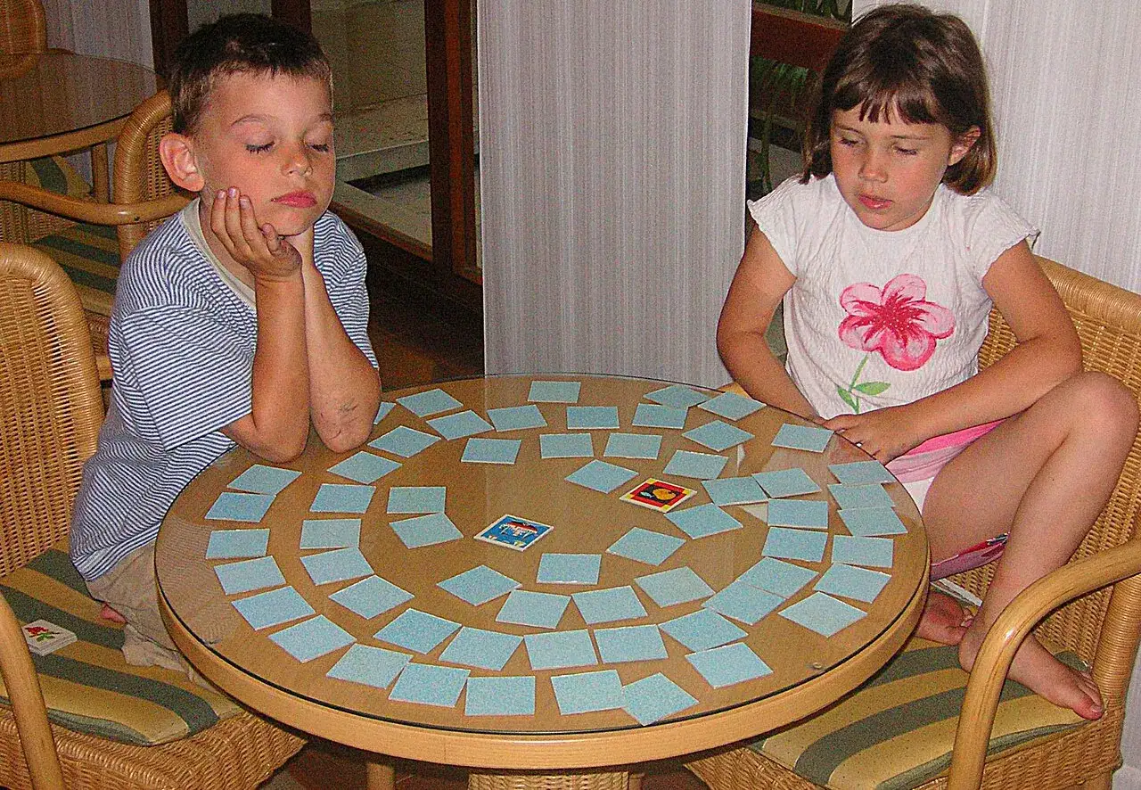 Bambini concentrati su un tavolo con carte per giochi di memoria.