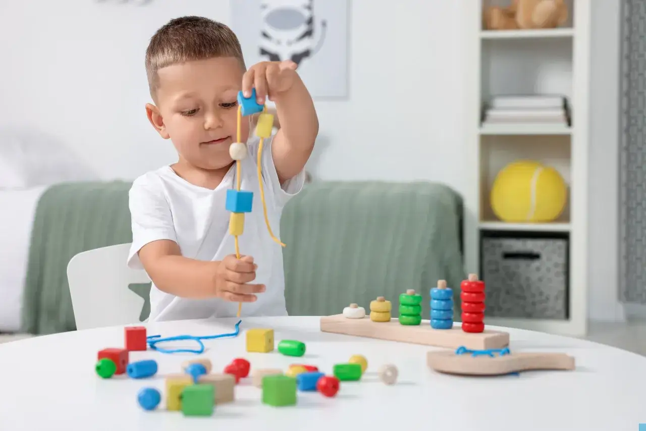 Bambino gioca con blocchi colorati e perline, perfetti giochi per migliorare l'impugnatura.