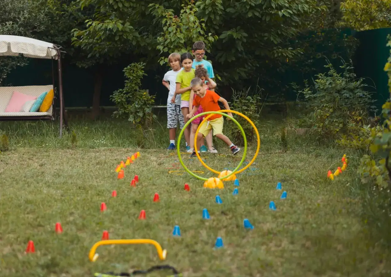 Bambini si divertono con giochi da fare in giardino: corrono tra coni colorati e cerchi, pronti per una gara di agilit&agrave;.