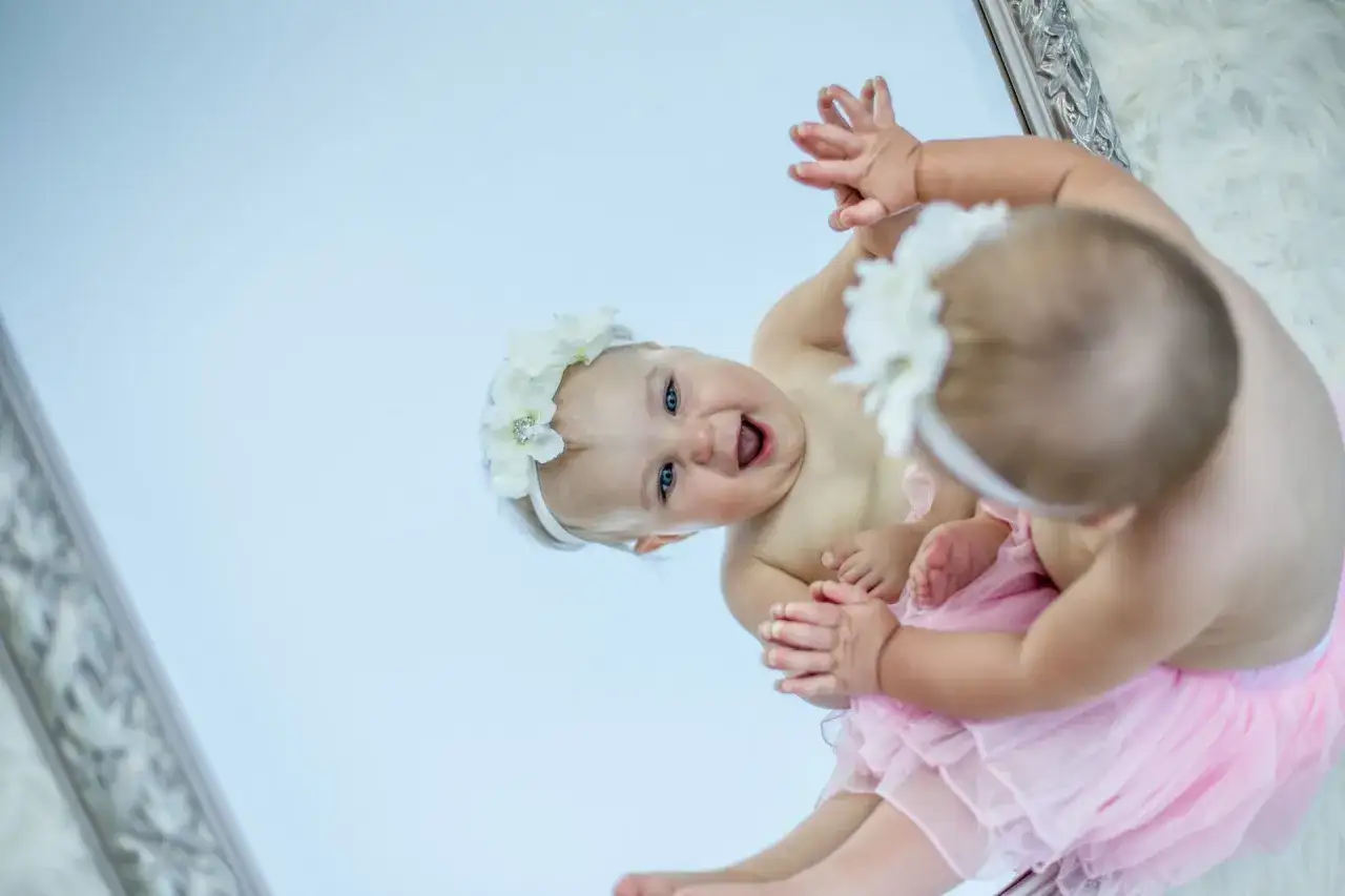 Bambina con coroncina di fiori e tut&ugrave; rosa, riflessa in uno specchio. Un'immagine che cattura la gioia e la crescita dei bambini.
