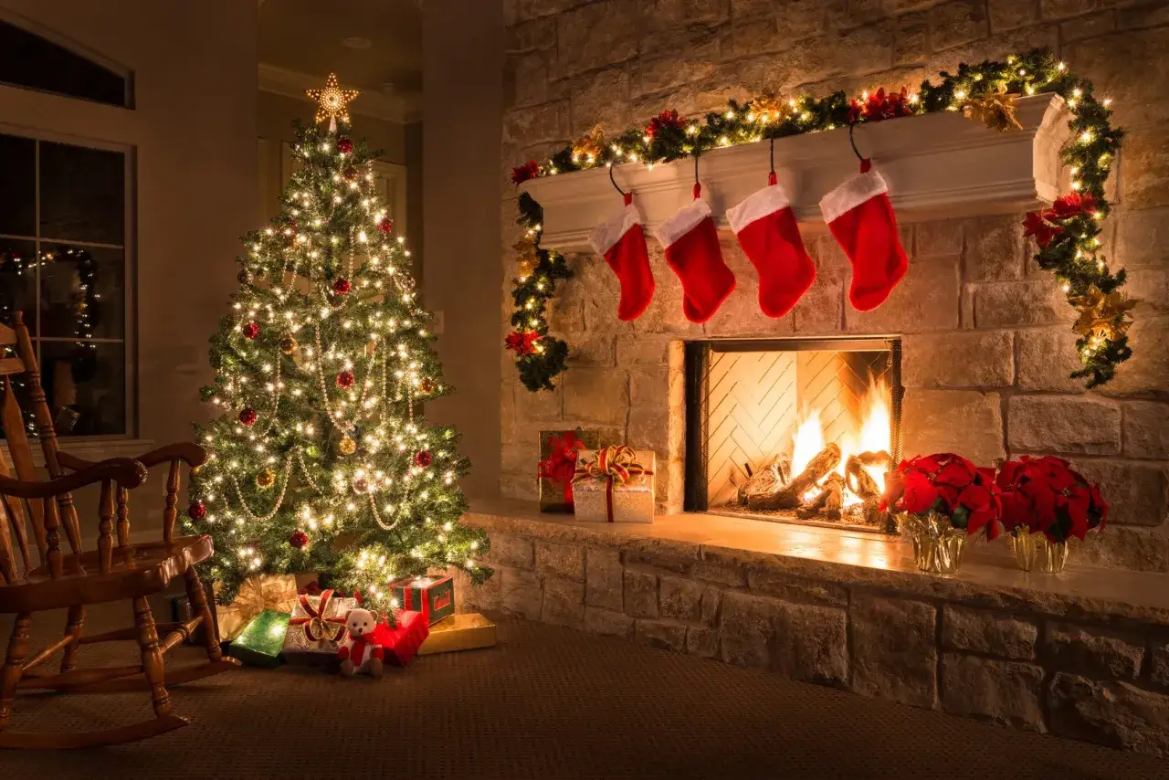 Un albero di Natale illuminato, con regali e calze rosse appese al camino acceso. Un'atmosfera magica, simbolo albero di natale.