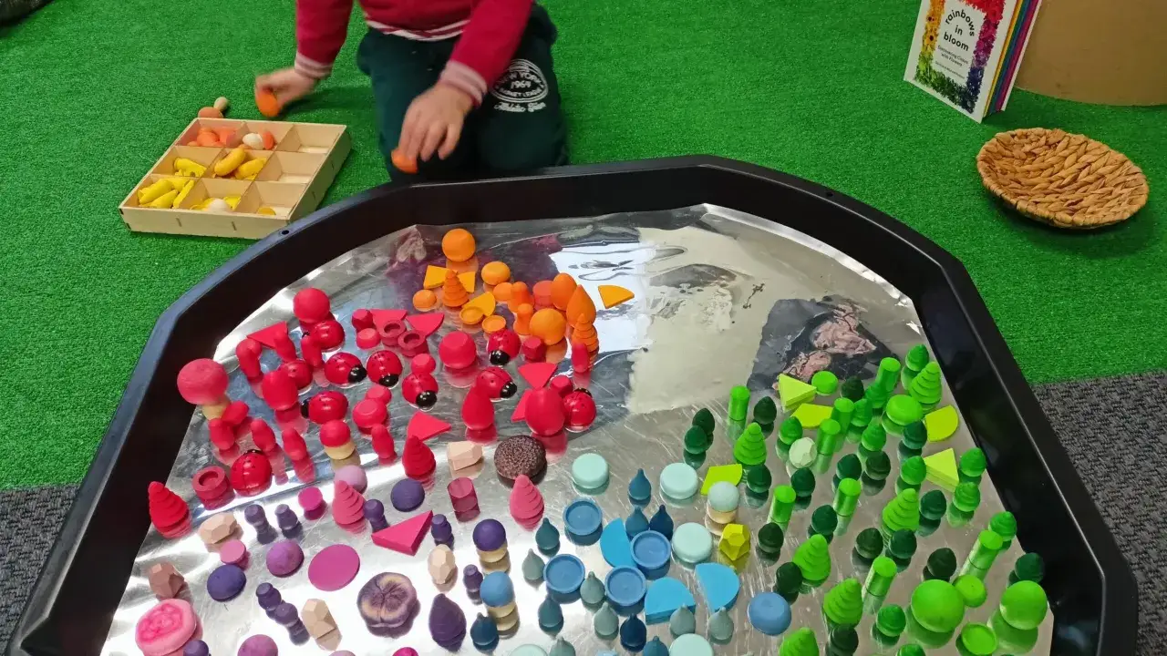 Bambino gioca con blocchi colorati in un vassoio, parte di una terapia occupazionale per bambini.