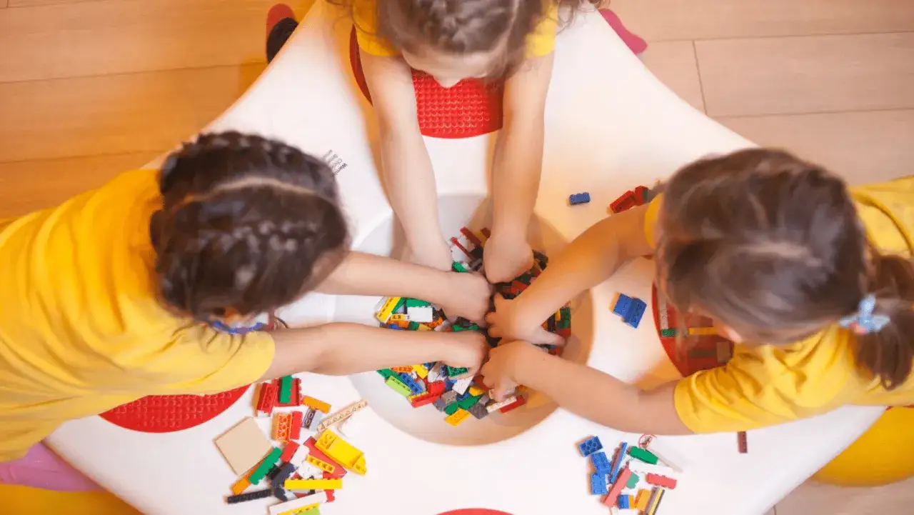Bambini con magliette gialle giocano con mattoncini colorati, un modo divertente per stimolare il linguaggio e la creatività.