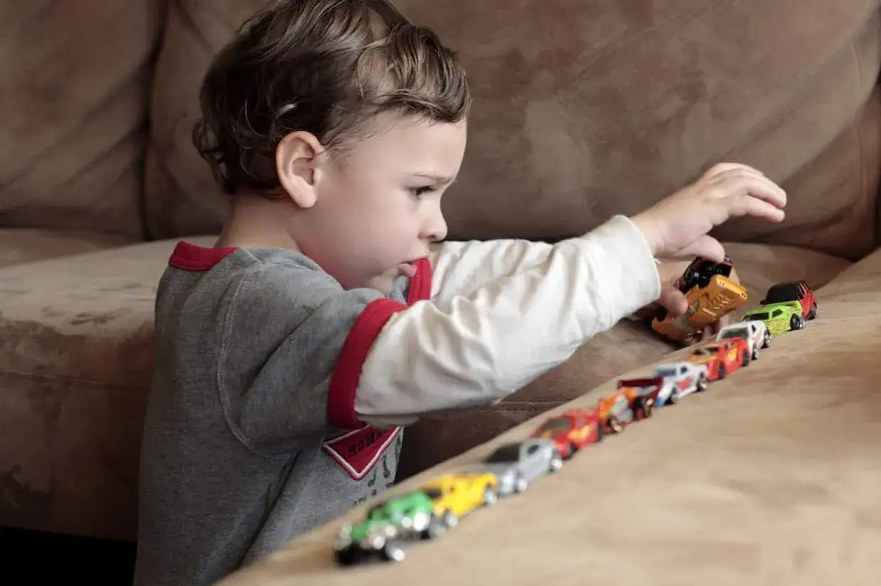 Bambino allinea macchinine colorate, un esempio di stimming.