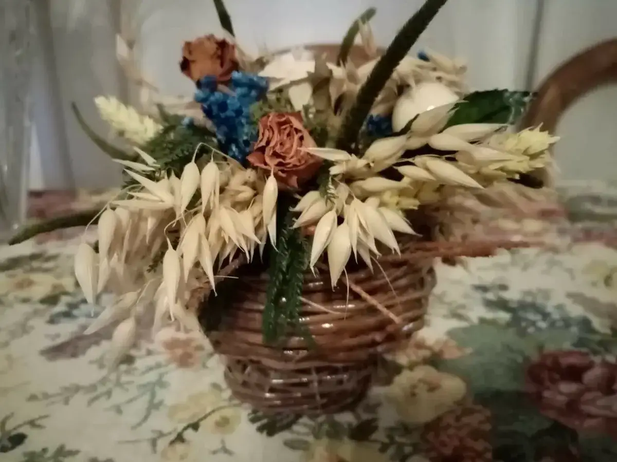 Composizione rustica con fiori secchi e spighe in una cesta di vimini, un'idea su come abbellire una cesta di vimini con elementi naturali.