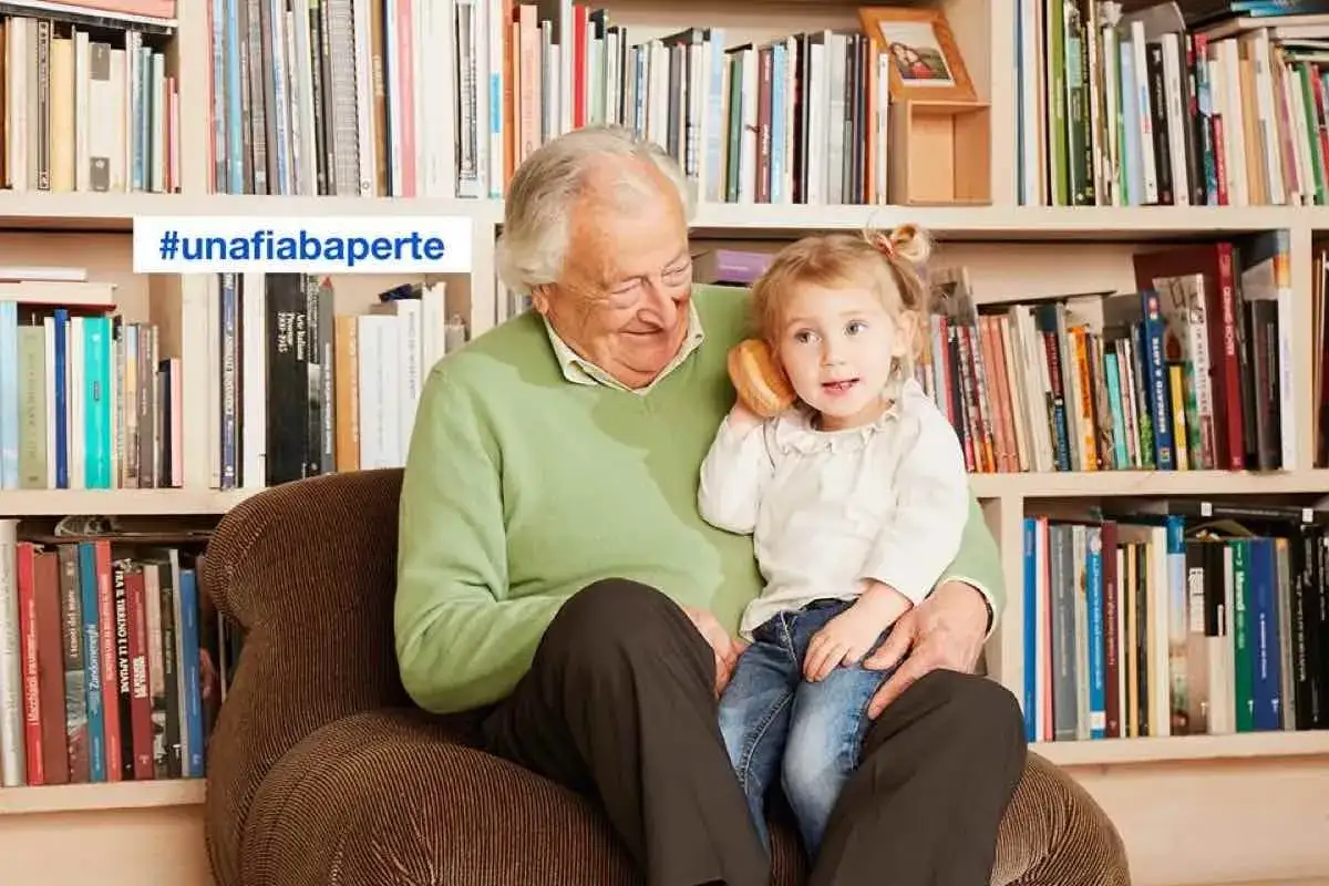 Nonna e nipote ascoltano audio fiabe, circondati da libri.