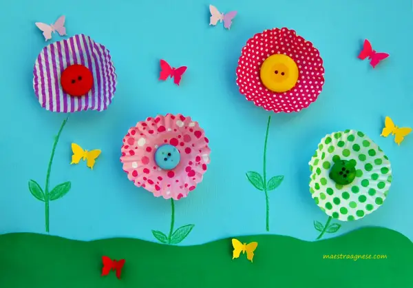 Lavoretti primavera: fiori colorati con bottoni e farfalle di carta su sfondo azzurro.