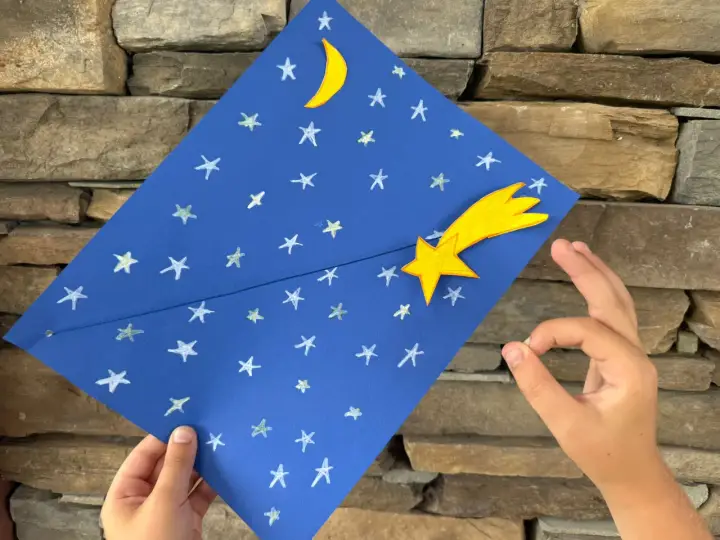 Un cielo blu con stelle e luna, una stella cometa gialla. Un lavoretto per bambini, stella di natale.